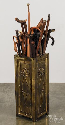 Embossed brass cane stand, together with a large assortment of canes.