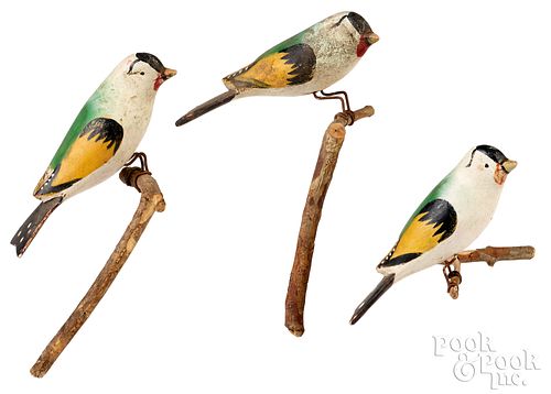 Three carved and painted birds on perches