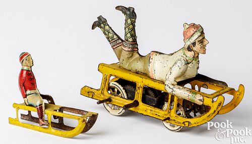 Two tin lithograph boy on sled penny toys