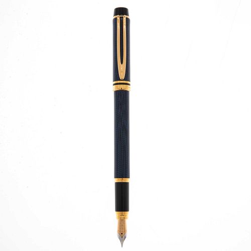 Artículos de escritura pluma fuente Waterman. Cuerpo en acero color azul. Punto en oro amarillo de 18k. Estuche original.