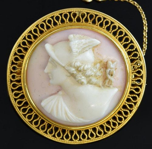 A carved pink shell cameo brooch depicting the profile of Mercury within a gold wire border mounted in unmarked yellow metal.