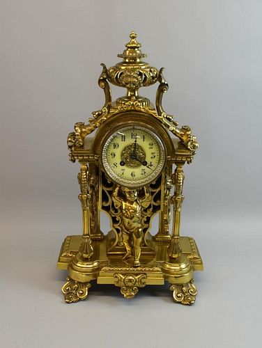 Brass mantel clock with central putti holding up the clock drum flanked by columns, on scroll feet, 48cm high,