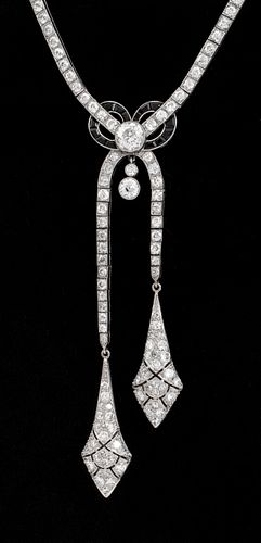 Hand fabricated platinum, diamond, and onyx necklace, designed in the Art Deco style, featuring ribbon and bow motifs, with double drop tassels, adorn