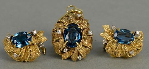 Three piece 14K gold set with pendant and matching pierced earrings, each mounted with oval blue stone and small diamonds. 
t