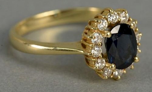 18K gold ring set with blue sapphire surrounded by diamonds. 4.8 grams