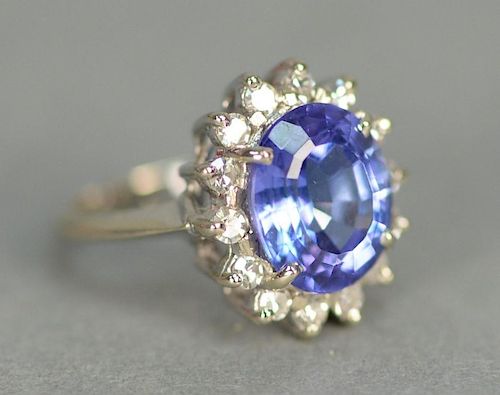 14K white gold ring set with center blue tanzanite surrounded by 14 diamonds.