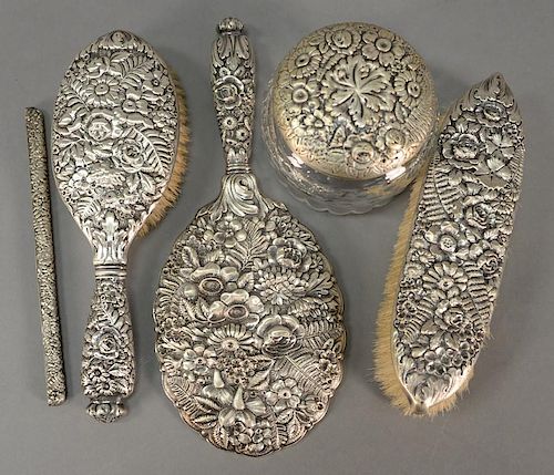 Five piece Tiffany & Co. floral repousse sterling silver dresser set comprising of a hand mirror, hairbrush, part of a comb, 