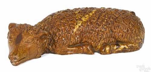 Redware figure of a reclining lamb, 19th c., with mottled orange and yellow glaze, 11 3/4'' l.