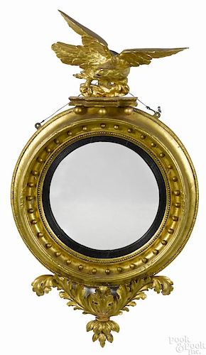 Giltwood convex mirror, ca. 1800, with an eagle crest and foliate pendant, 54'' h.
