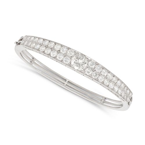 A DIAMOND BANGLE set with a round brilliant cut diamond of approximately 1.24 carats, accented by...
