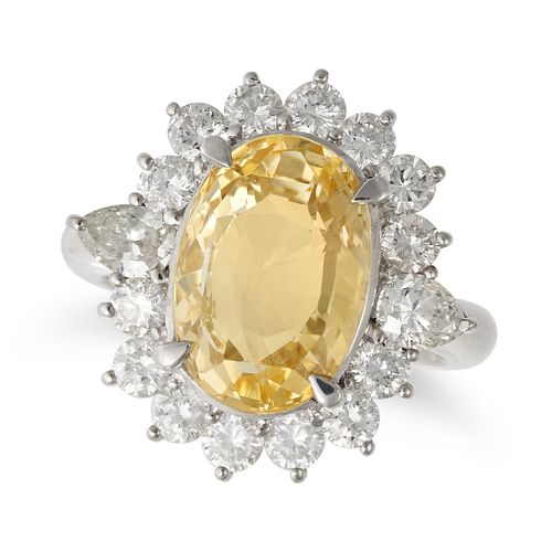 A YELLOW SAPPHIRE AND DIAMOND CLUSTER RING in platinum, set with an oval cut yellow sapphire of 7...