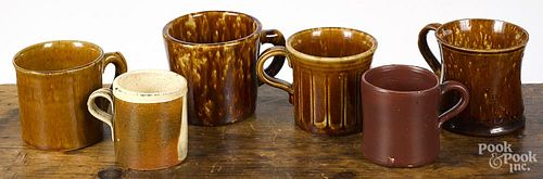 Four Bennington flint enamel mugs, together with a redware frog mug and a mocha type mug