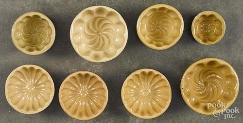 Eight yellowware food molds with pinwheel centers, largest - 4'' dia.