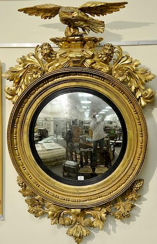 Caved and gilt convex mirror mounted with eagle flanked by two lions and foliate carving on circular deep cove with ebonized 