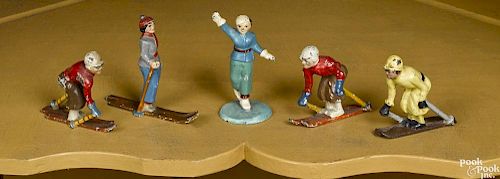 Four Hubley cast iron skiers, tallest - 3'', together with a figure skater, 3 1/4'' h.