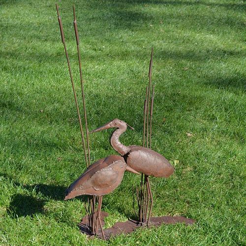A wrought-iron sculptural group of two shorebirds, a sandpiper and heron, standing among cattails