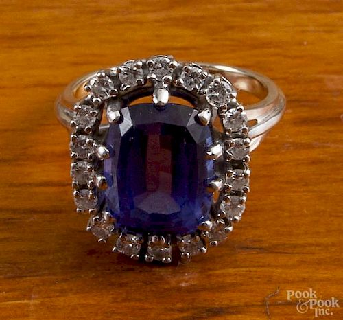 18K white gold ring with a large center oval blue sapphire surrounded by round diamond accents