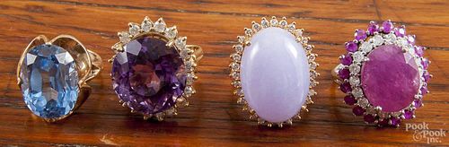 Four 14K yellow gold rings with large center stones such as blue topaz, amethyst, ruby, and lavendar