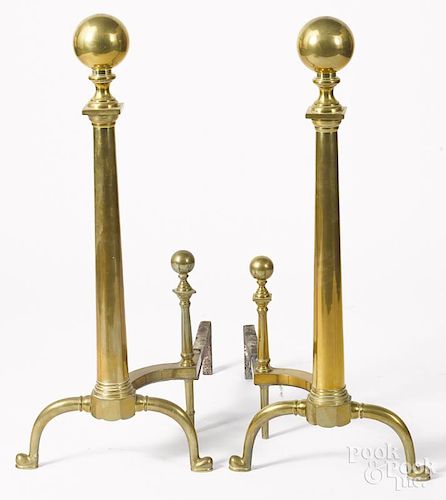 Pair of large brass andirons, 20th c., 34'' h., together with a fender, 9'' h., 42'' w.