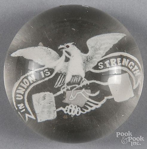 White frit paperweight, with an American Eagle sitting upon clasped hands, with a banner inscribed