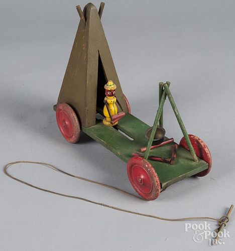 Unusual animated wood pull toy of a man emerging from a teepee and placing wood on a fire, 10'' h. an
