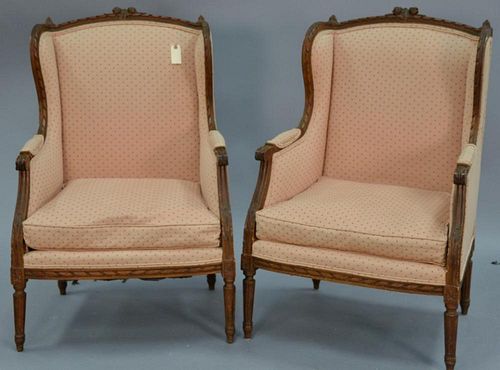 Pair of Louis XVI style upholstered fauteuils, winged back with carved frame.