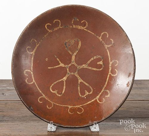 Long Island redware charger, 19th c., with yellow slip heart decoration, 12'' dia.