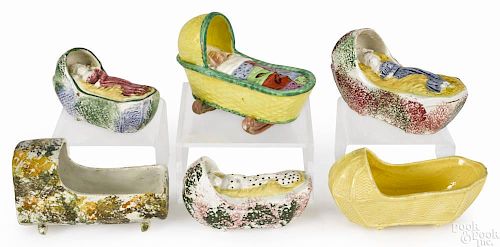 Six Staffordshire cradles, early 19th c., to include four examples with a sleeping baby inside, a
