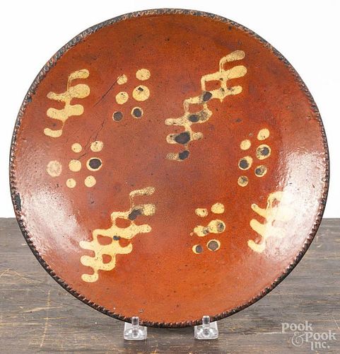 Pennsylvania redware plate, ca. 1800, with slip decorated dots and triple wavy lines, 10'' dia.