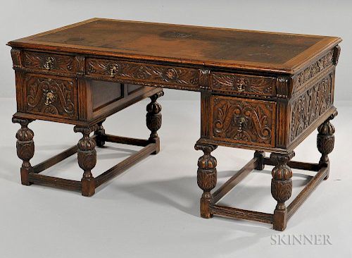 Jacobean-style Oak Writing Desk, late 19th/early 20th century, with a leather-inset top and foliate carved drawer fronts on f