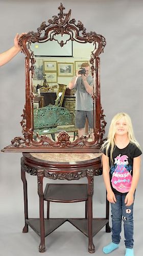 Oriental demilune table with mirror, having inset marble top over carved skirt and three curio shelves. ht. 31in., wd. 33in.,