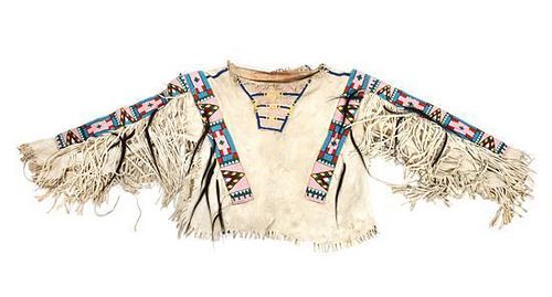 A Crow Style Boy's Hide Fringed and Beaded Shirt Maximum width 50 inches.
