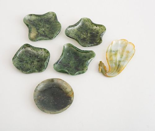 FOUR CHINESE CARVED SPINACH GREEN JADE LOTUS LEAF DISHES, A SPINACH GREEN JADE CIRCULAR DISH AND A SEAWEED JADE DRAGON-HEADED