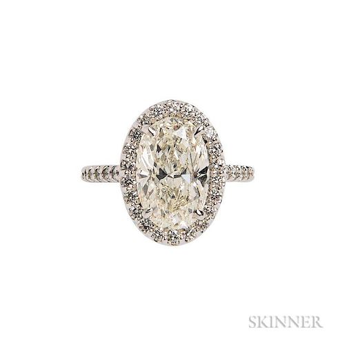 18kt White Gold and Diamond Solitaire, prong-set with an oval-cut diamond weighing 5.01 cts., framed by full-cut diamonds, si
