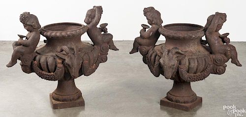 Pair of cast iron putti and rams head garden urns