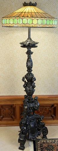Leaded and stained glass shade on bronze figural floor lamp base. ht. 76in., dia. 28in. Provenance: Property from the Estate