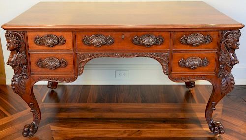 Mahogany partners desk having female leg supports on cabriole legs ending in large paw feet and carved pulls having glass top