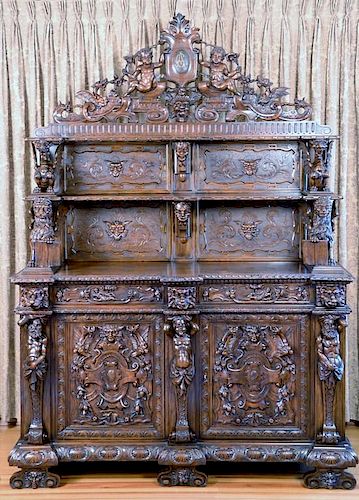 Walnut sideboard in two parts, upper portion with carved cupid crest with winged griffins over two shelves with gargoyles, fl