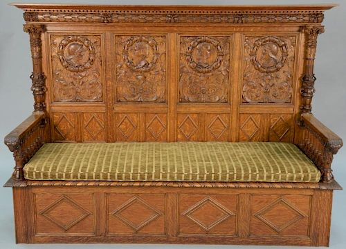 Carved oak bench back with carved knights and maidens and ram's head hand rests with spindled arms with lift seat