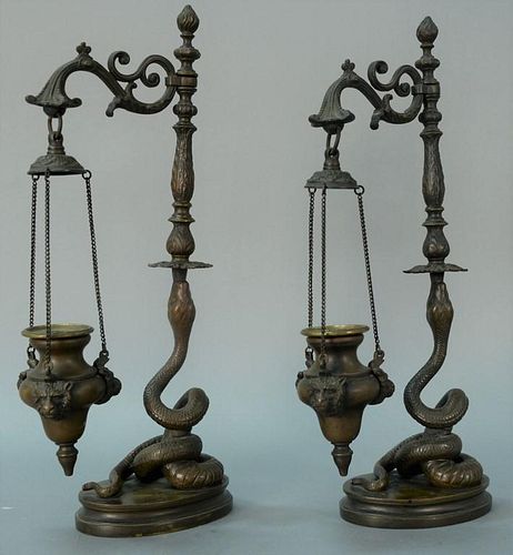 Pair of bronze oil lamps having scrolled arm with hanging font with bear masks, supported by coiled snake on base. ht. 16 3/4