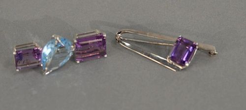 Two custom gold pins, one set with two amethyst and one blue stone, other set with one amethyst.