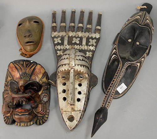 Group of four African masks to include two painted wood, one metal, and one mixed media. ht. 8in. to 27 1/2in.