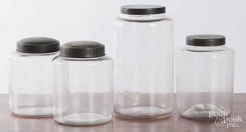 Four glass country store bottles with tin lids