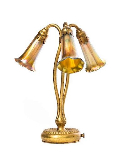A Tiffany Studios Dore Bronze and Gold Favrile Glass Three-Light Lily Table Lamp, Height overall 12 3/4 inches.