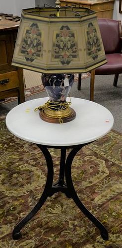 Two piece lot to include an iron parlor table with white penorcelain top (ht. 30in., dia. 24in.), and a marble lamp with tin 