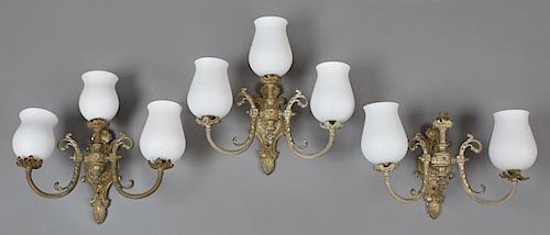 Set of Three French Gilt Brass Three Light Wall Sconces, c. 1930, the relief shell topped back plates issuing a central light