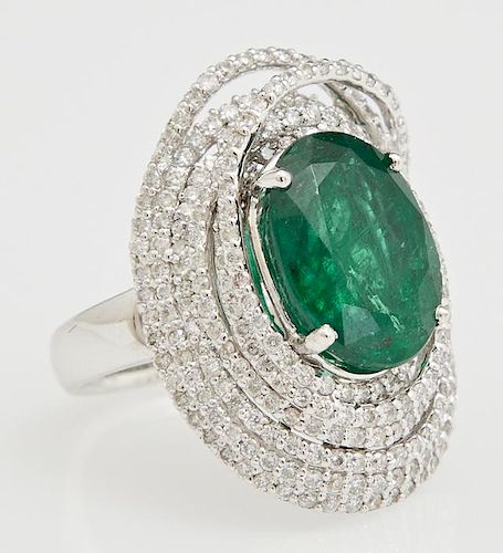 Lady's 18K White Gold Dinner Ring, with an oval 6.95 carats emerald centering swirled concentric bands of round diamonds, tot