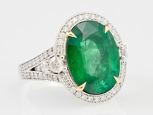 Lady's 18K White Gold Dinner Ring, with an oval 9.25 carat emerald atop a diamond mounted border, the pierced split shoulders