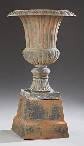 Large Cast Iron Campana Form Garden Urn, 20th c., with a relief everted rim over ribbed sides to a socle support on a square 