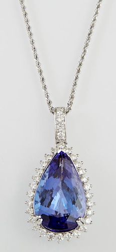 Platinum Pendant, with a 20.18 carat pear shaped tanzanite, within a conforming border of round diamonds, beneath a diamond m